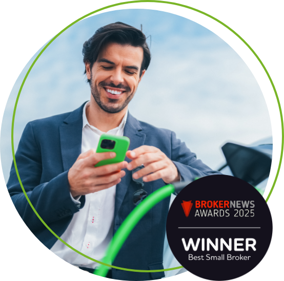 Man smiling looking at a phone whilst charging a car